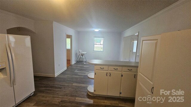 kitchen with white refrigerator with ice dispenser, crown molding, dark wood finished floors, a textured ceiling, and baseboards