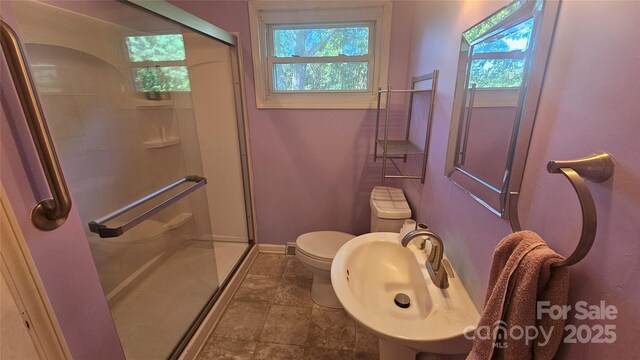 full bath with toilet, a shower stall, baseboards, and a sink