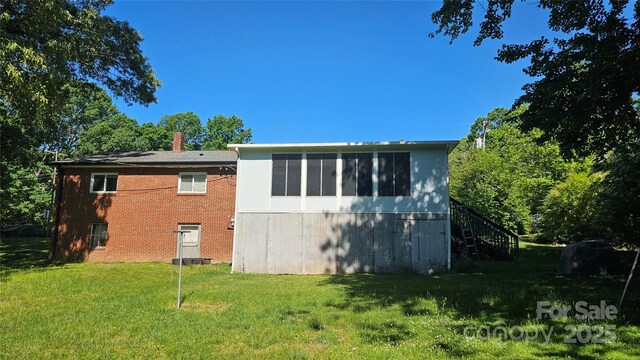 view of home's exterior featuring stairway, a yard, a chimney, and brick siding