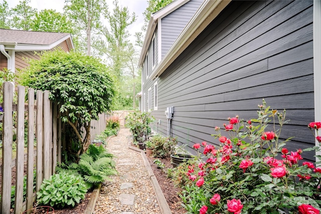 view of home's exterior featuring fence and a garden