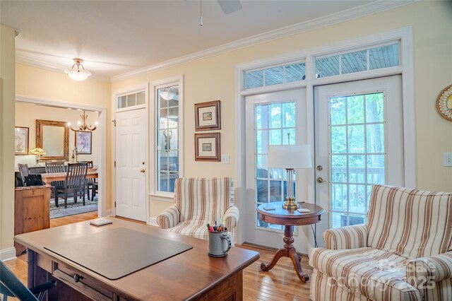 office space with a chandelier, light wood finished floors, ornamental molding, and a ceiling fan