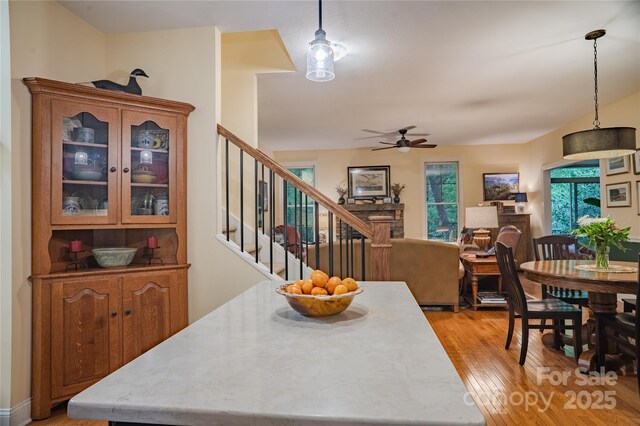 dining space with a ceiling fan, light wood finished floors, and stairs