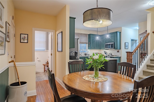 dining room featuring light wood-style floors, stairway, and baseboards