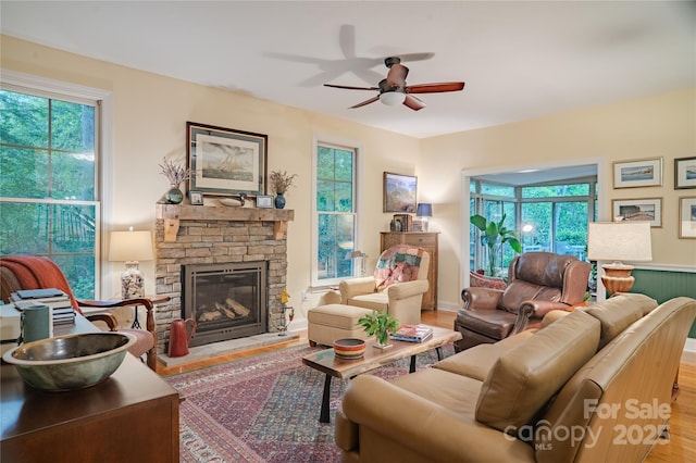 living area featuring a ceiling fan, healthy amount of natural light, a fireplace, and wood finished floors