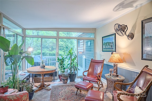 sunroom / solarium featuring crown molding and a wainscoted wall