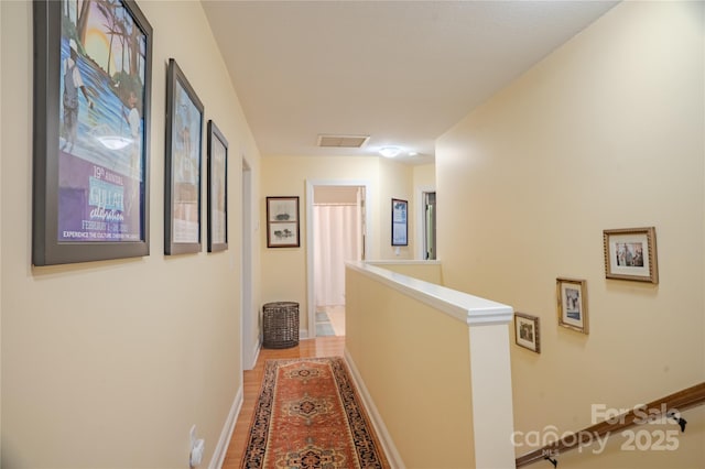 hall with an upstairs landing, light wood-type flooring, and baseboards