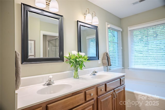 bathroom with plenty of natural light, double vanity, and a garden tub