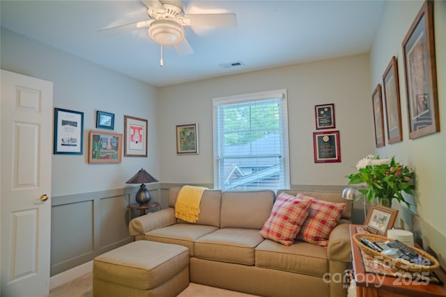 living room featuring a ceiling fan and wainscoting