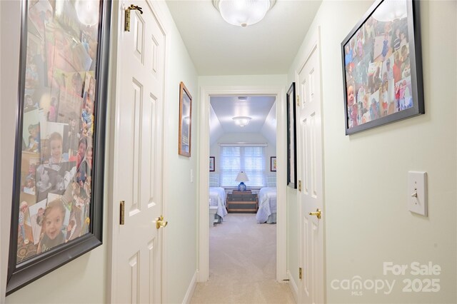 corridor with light colored carpet and vaulted ceiling