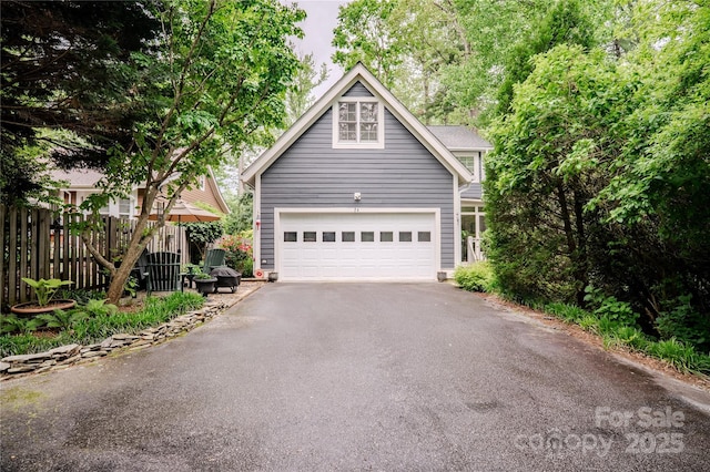 view of front of property featuring driveway, fence, and a garage