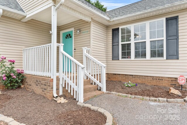 view of exterior entry featuring a shingled roof and crawl space