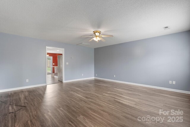 empty room with ceiling fan, wood finished floors, a textured ceiling, and baseboards