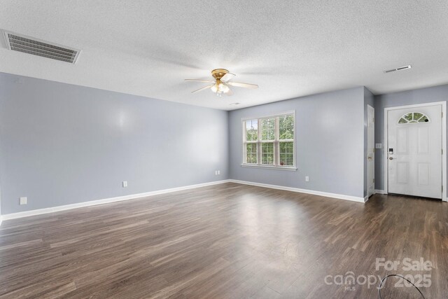 empty room featuring a ceiling fan, dark wood-style flooring, baseboards, and a textured ceiling
