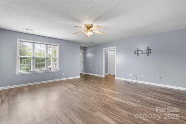 spare room featuring ceiling fan, wood finished floors, a textured ceiling, and baseboards