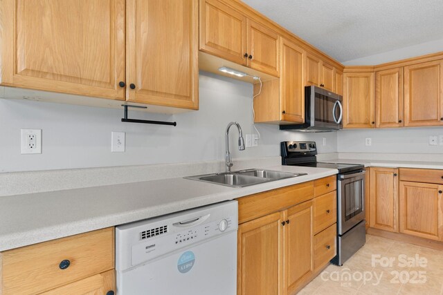 kitchen with appliances with stainless steel finishes, a sink, light countertops, and light tile patterned floors