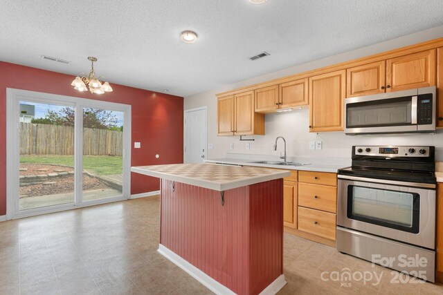 kitchen featuring stainless steel appliances, light countertops, a sink, a chandelier, and a textured ceiling