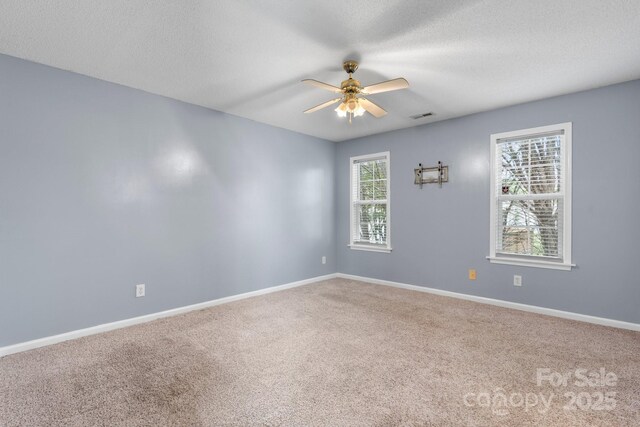 unfurnished room with carpet flooring, ceiling fan, baseboards, and a textured ceiling
