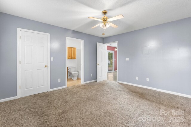 unfurnished bedroom with light carpet, connected bathroom, baseboards, and a ceiling fan