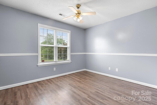 spare room featuring wood finished floors, ceiling fan, baseboards, and a textured ceiling