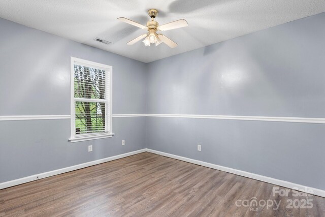empty room featuring wood finished floors, ceiling fan, baseboards, and a textured ceiling