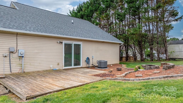 back of house featuring a fire pit, a shingled roof, a deck, central AC, and a yard