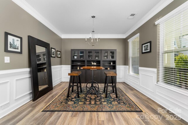 3615 Alamito Ln, Charlotte, NC 28214 - dining room with a chandelier, dark wood-style flooring, a wainscoted wall, crown molding, and a decorative wall