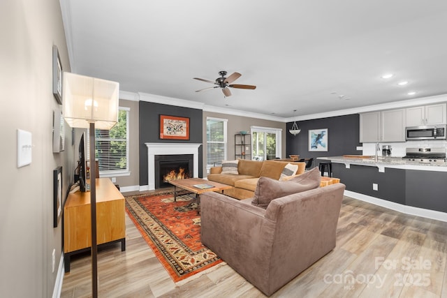 3615 Alamito Ln, Charlotte, NC 28214 - living area featuring ceiling fan, light wood-style flooring, ornamental molding, baseboards, and a lit fireplace
