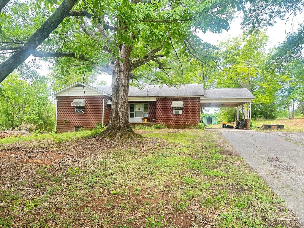 ranch-style home featuring a carport, asphalt driveway, and brick siding