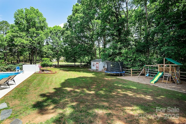 view of yard with a shed, a playground, an outdoor structure, and view of wooded area