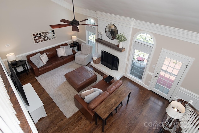 living room featuring wood finished floors, a ceiling fan, crown molding, a fireplace, and vaulted ceiling