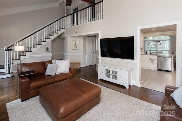 living room with crown molding, stairway, wood finished floors, a high ceiling, and baseboards