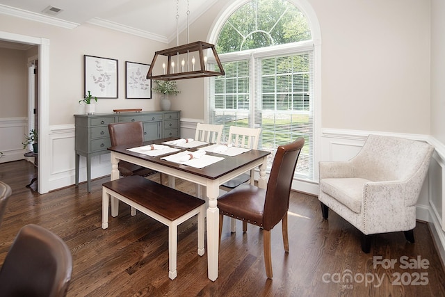 dining room with a decorative wall, wainscoting, dark wood-type flooring, and ornamental molding