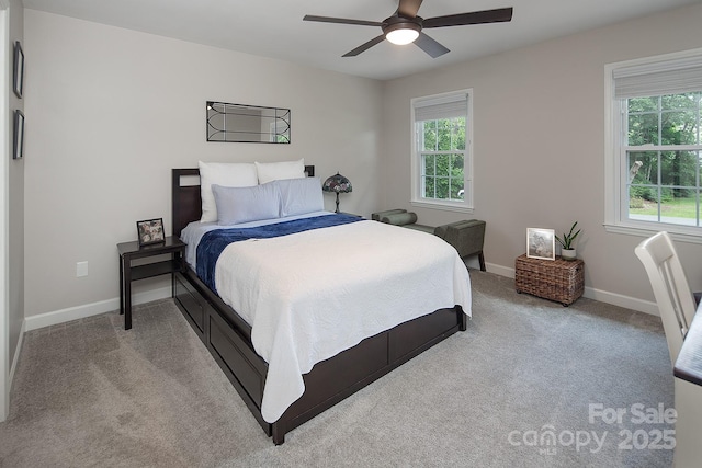bedroom featuring multiple windows, light colored carpet, baseboards, and ceiling fan