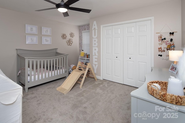 bedroom with carpet flooring, a closet, a crib, and ceiling fan