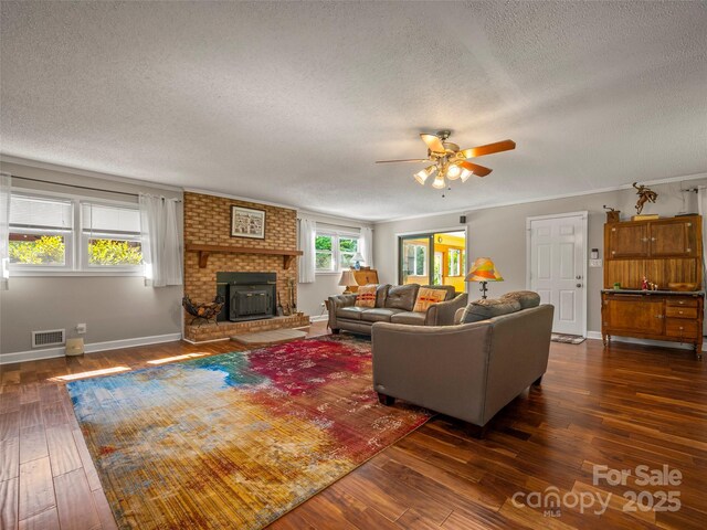 living area with a textured ceiling, dark wood finished floors, a ceiling fan, a fireplace, and baseboards