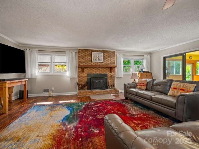 living room featuring a textured ceiling, hardwood / wood-style floors, ornamental molding, and baseboards