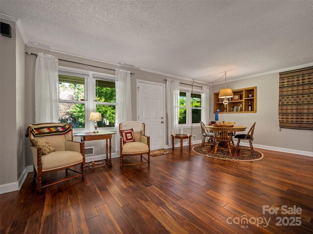 dining space featuring a textured ceiling, hardwood / wood-style flooring, crown molding, and baseboards