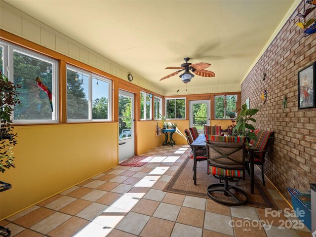 sunroom / solarium featuring brick wall and tile patterned floors