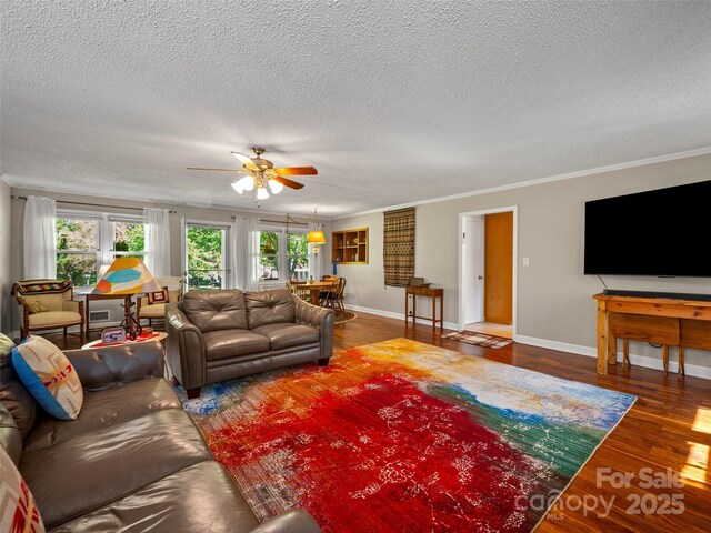 living room featuring a textured ceiling, ceiling fan, wood finished floors, baseboards, and ornamental molding
