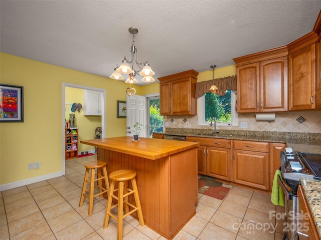 kitchen with wood counters, decorative backsplash, a sink, light tile patterned floors, and a textured ceiling