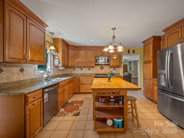 kitchen with appliances with stainless steel finishes, a sink, butcher block counters, backsplash, and a breakfast bar area