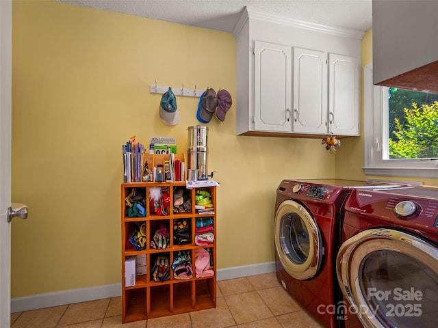 laundry area featuring washer and clothes dryer, cabinet space, light tile patterned floors, and baseboards