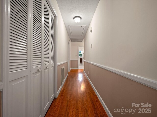 hallway with attic access and wood finished floors