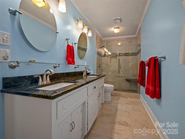 full bathroom with ornamental molding, a shower stall, double vanity, toilet, and baseboards
