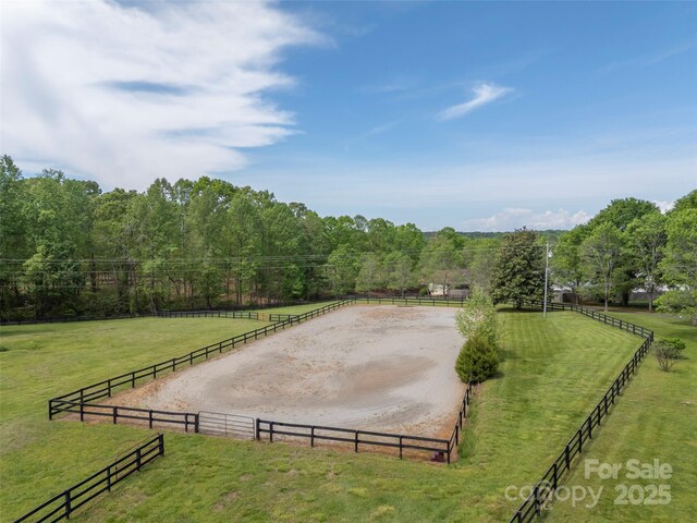 view of yard featuring driveway, an enclosed horse arena, and a rural view