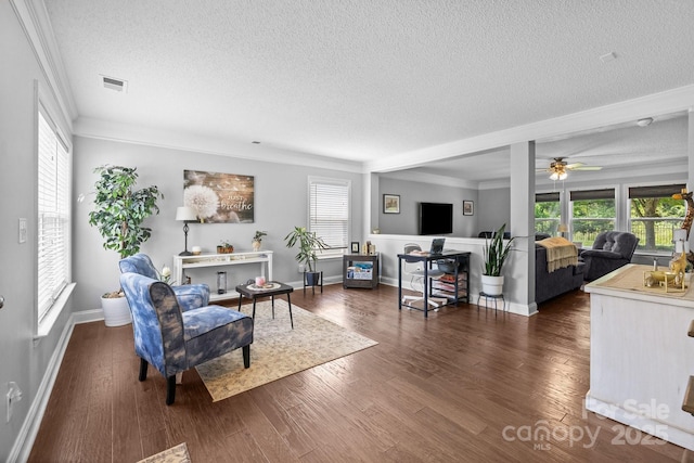 living room featuring a textured ceiling, plenty of natural light, ornamental molding, a ceiling fan, and dark wood finished floors