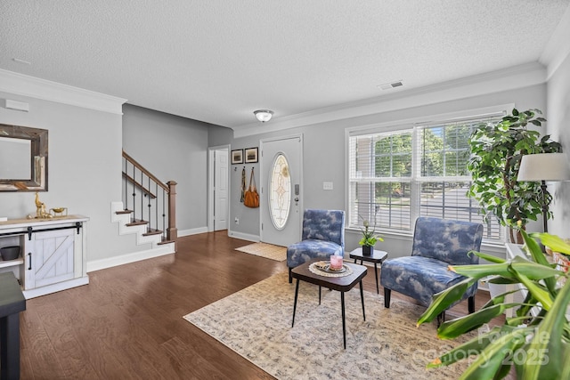 foyer with wood finished floors, stairs, a textured ceiling, crown molding, and baseboards