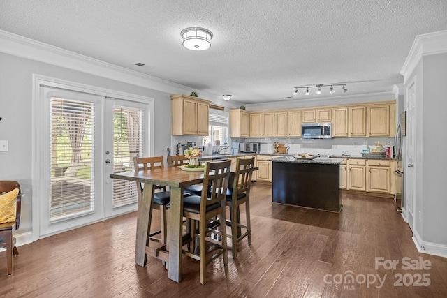 dining area with ornamental molding, a textured ceiling, dark wood-type flooring, plenty of natural light, and french doors