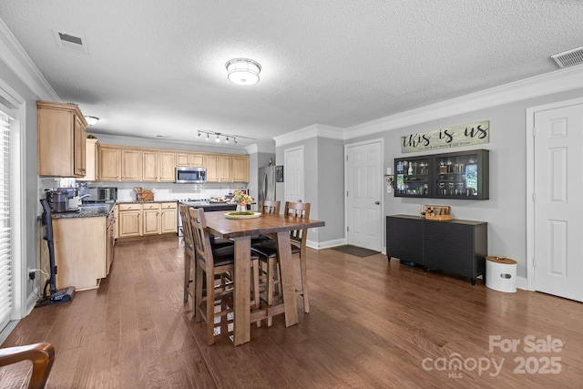 dining space with ornamental molding, a textured ceiling, and dark wood-style floors