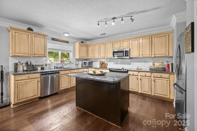 kitchen with appliances with stainless steel finishes, a sink, dark wood finished floors, decorative backsplash, and ornamental molding